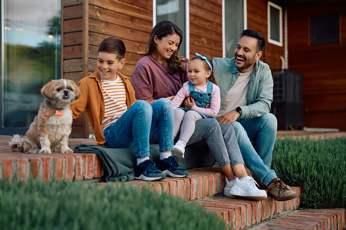 Happy kids and their parents enjoying with their pet in the backyard.
